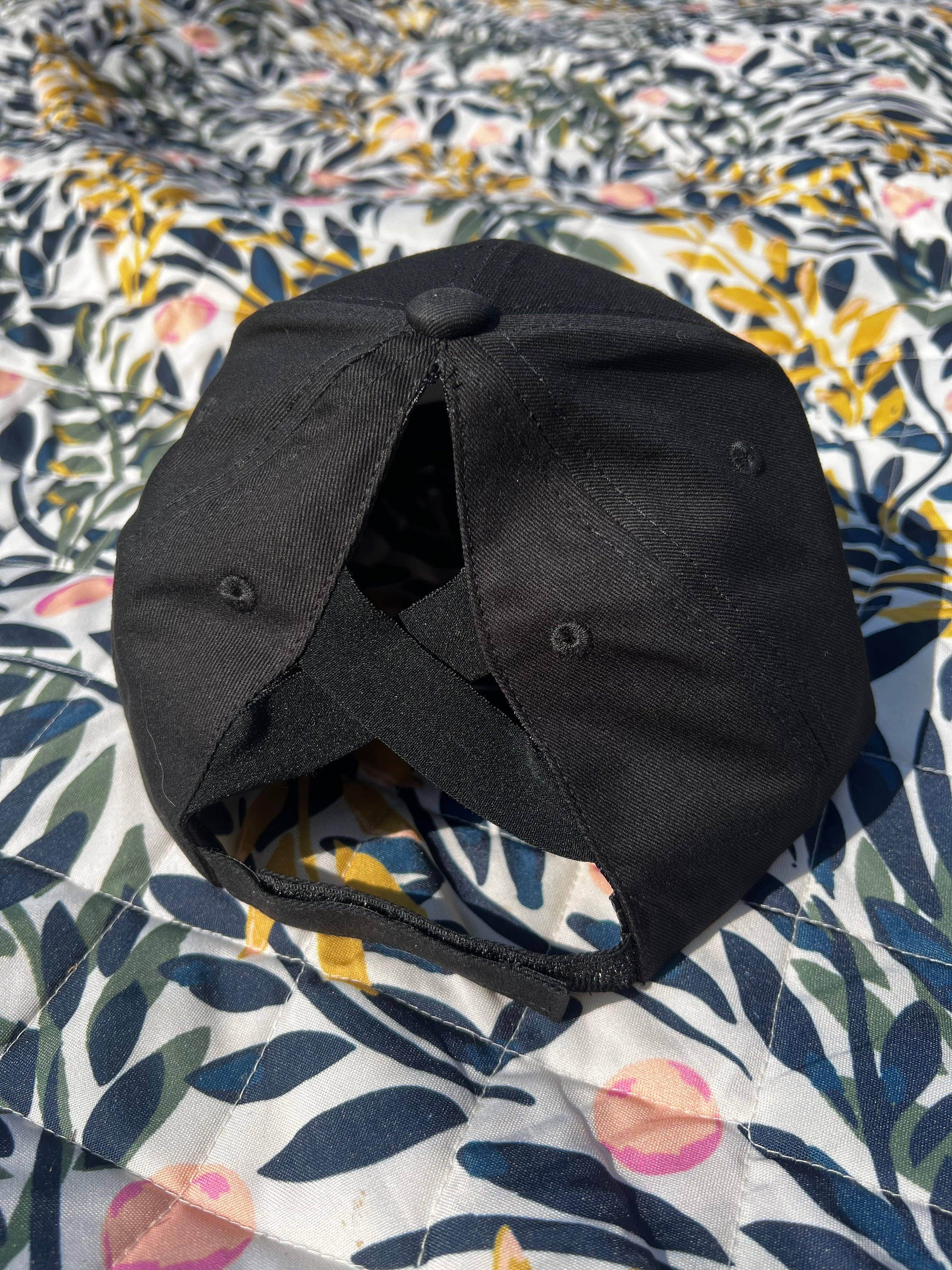 Black ponytail baseball cap on a floral-patterned fabric background