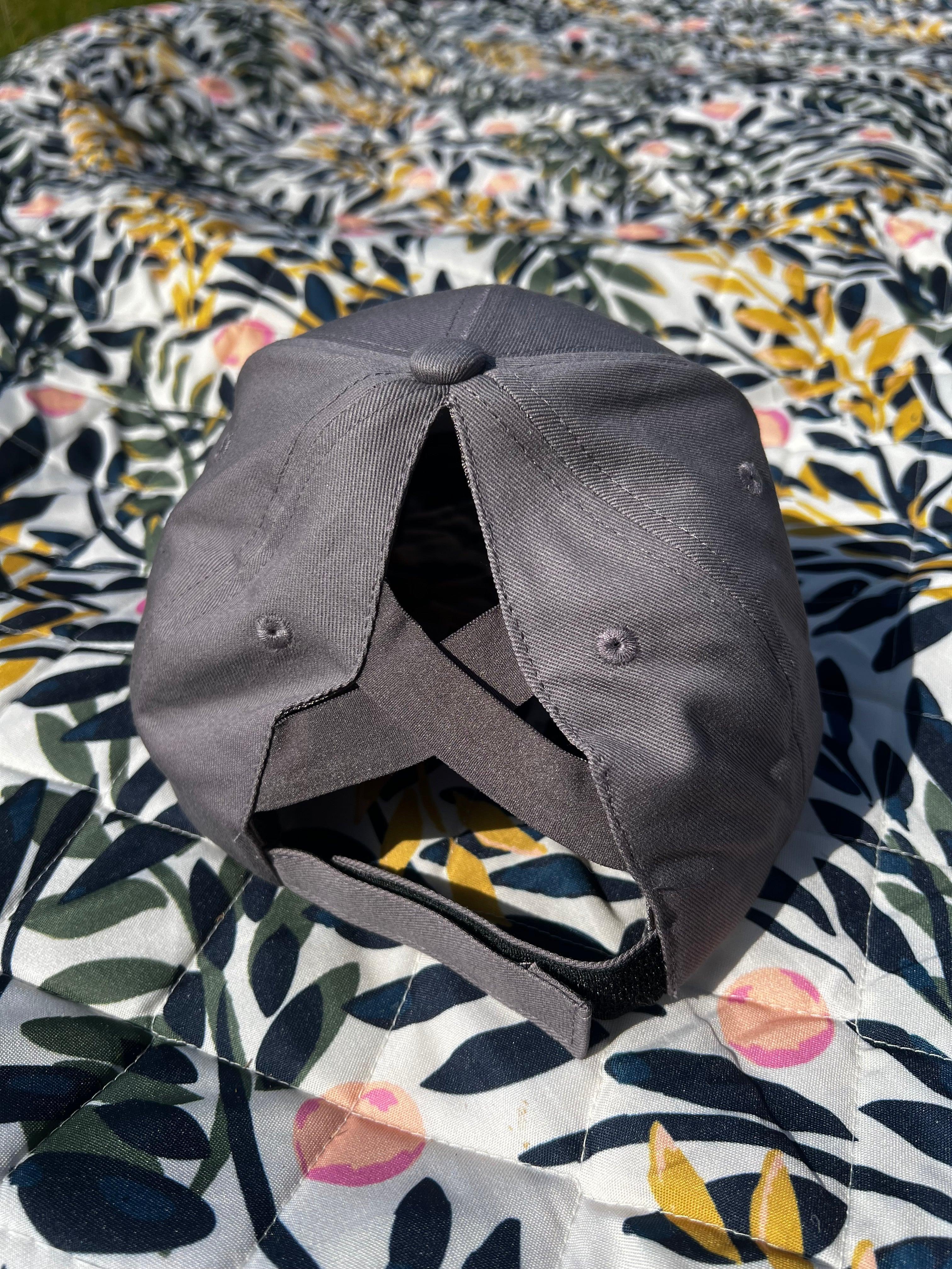 Grey ponytail baseball cap on a floral patterned surface