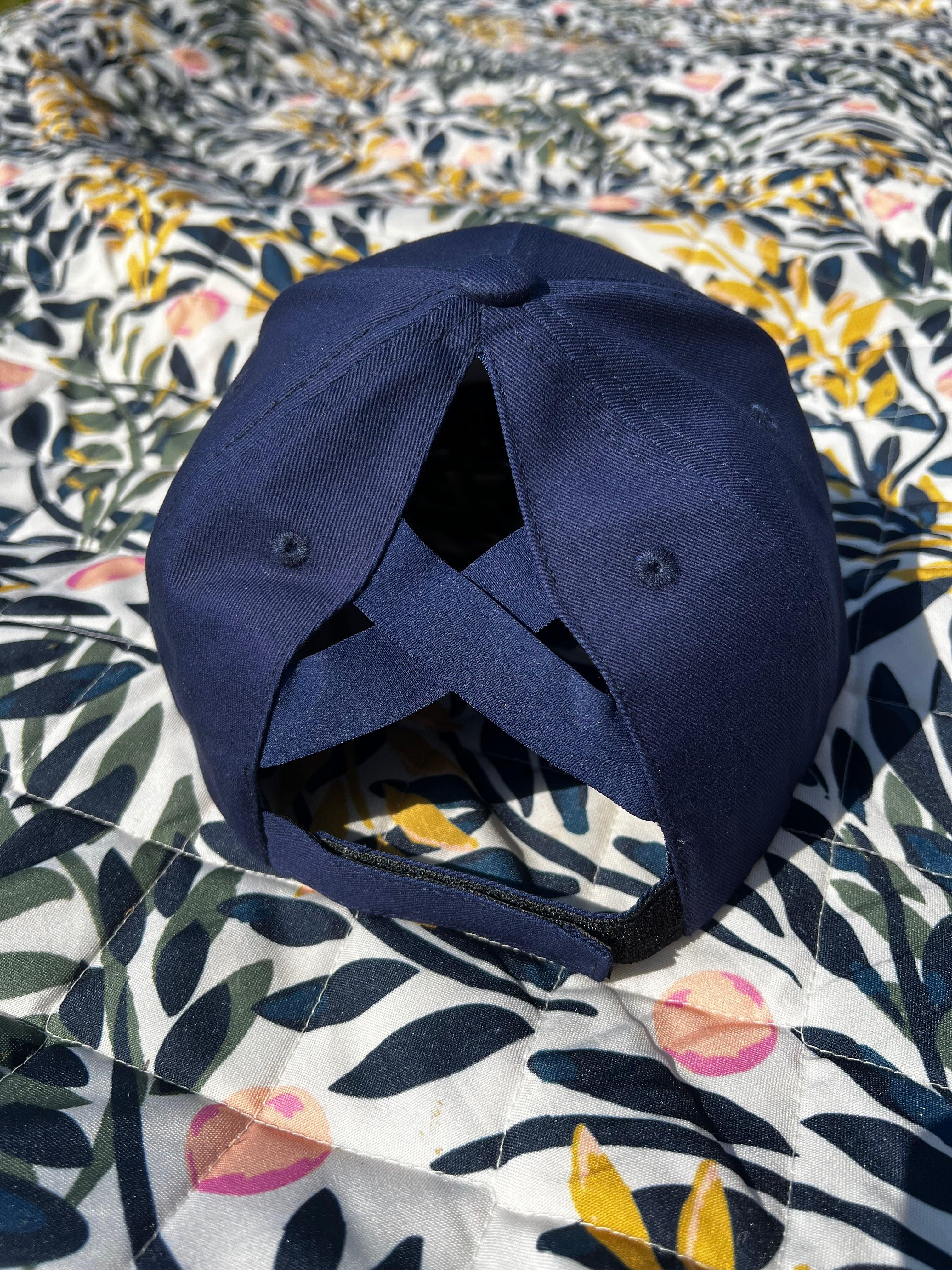 Navy blue ponytail baseball cap on a floral-patterned background