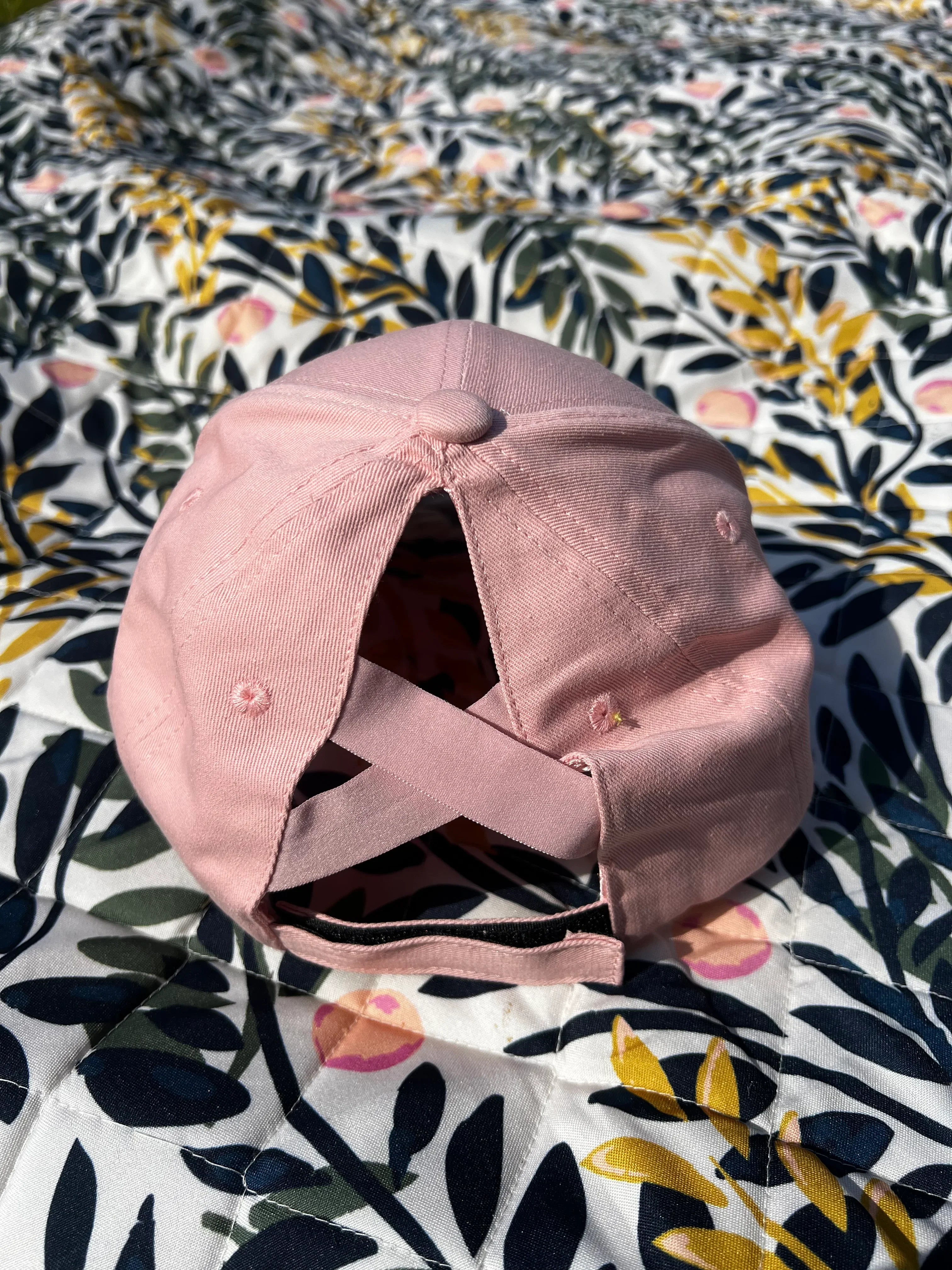 Pink ponytail baseball cap on a floral fabric background