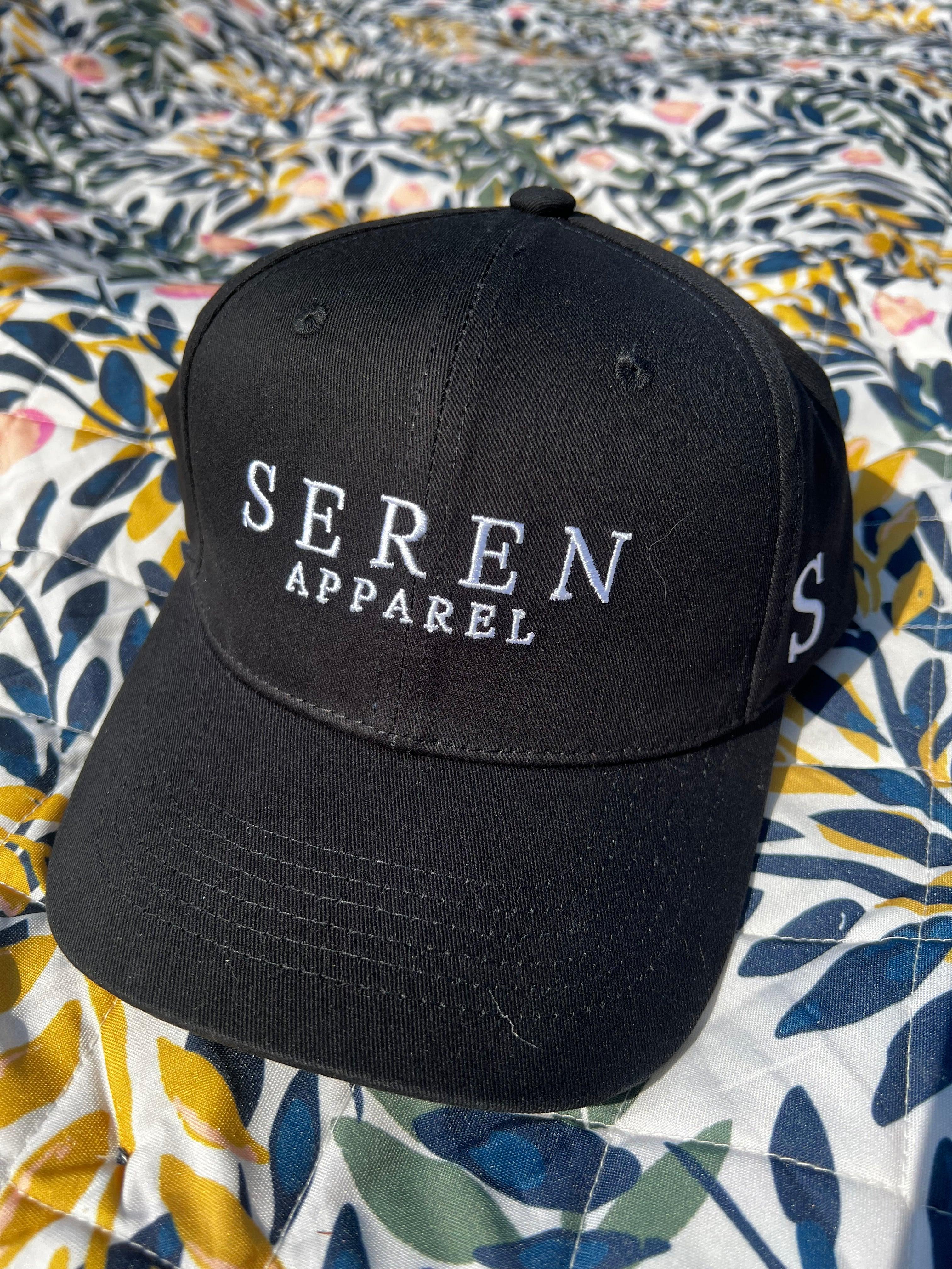 Black ponytail cap with 'Seren Apparel' branding on a patterned fabric background